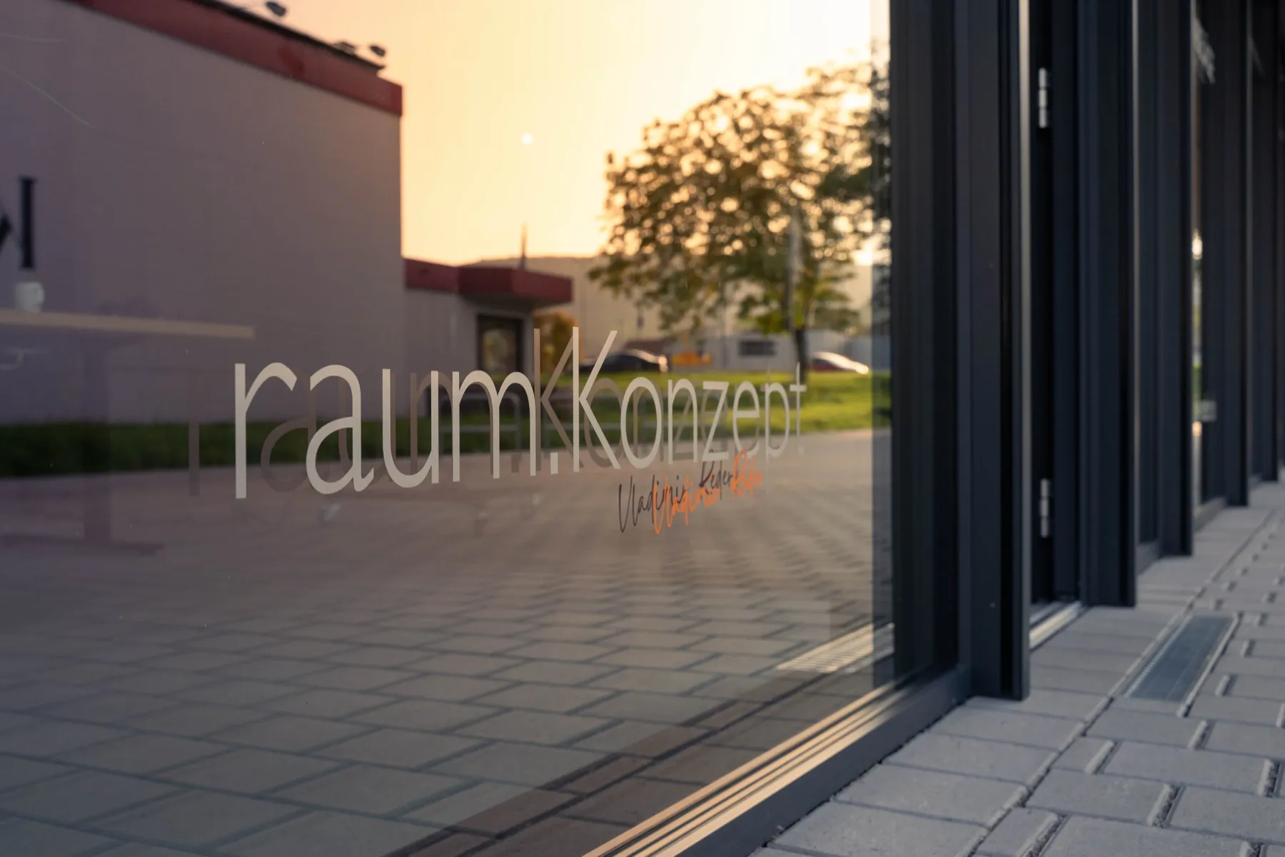 Firmensitz von raum.Konzept in Auggen mit Logo auf der Glasfassade in der Abendsonne