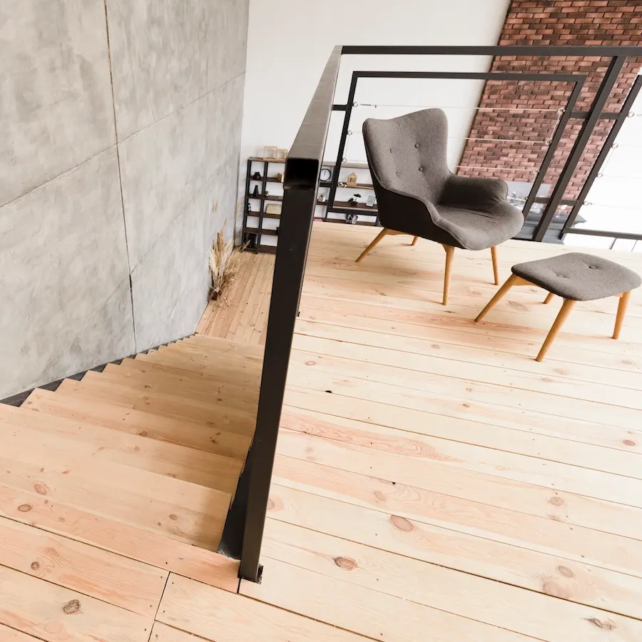 Loft mit hellem Dielenboden und Designsessel